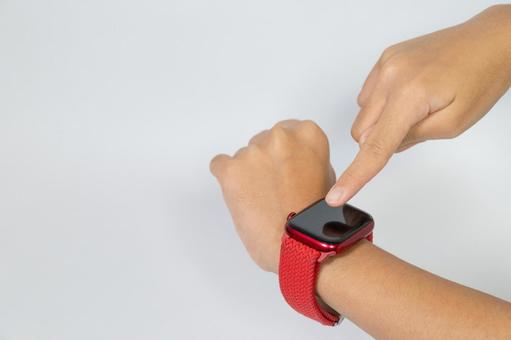 スマートウォッチを操作する赤いバンドの手 スマートウォッチを操作する赤いバンドの手 スマートウォッチ,時計,操作の写真素材