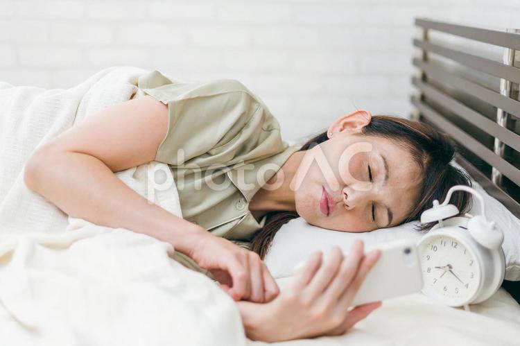 スマホを見るミドル世代の女性（寝る） 寝落ち,寝る前,スマホの写真素材