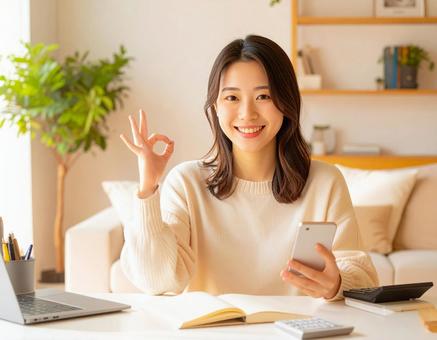 家計がうまくいきスマホ片手に微笑む女性 家計がうまくいきスマホ片手に微笑む女性の写真