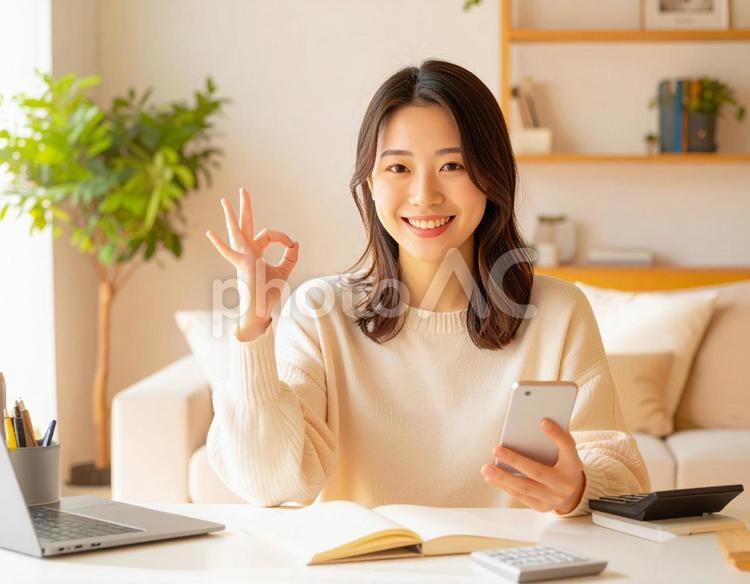 家計がうまくいきスマホ片手に微笑む女性 パソコン,家計簿,節約の写真素材