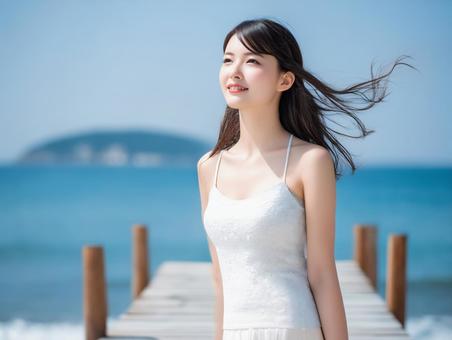 青空と海と白い夏服の女性の写真