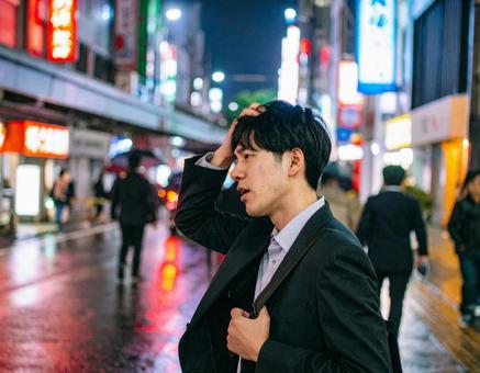 夜の街で疲れた表情を見せるビジネスマン 夜の街で疲れた表情を見せるビジネスマンの写真