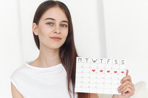 月経期間を示すカレンダーを手に持った女性 生理,月経,女性の写真素材