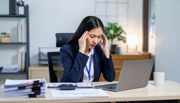 画面を見ながら頭を抱えるビジネスウーマンの写真