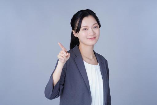 指差しして笑顔のスーツを着た女性 女性,指差し,ポーズの写真素材