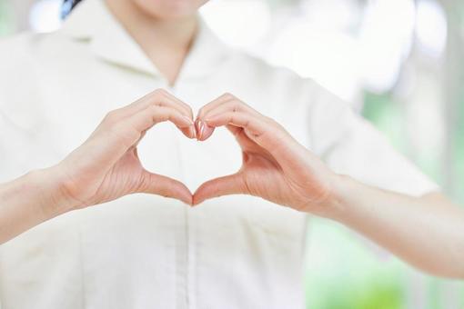 Female nurse making a heart mark with her fingers, JPG Female nurse making a heart mark with her fingers, JPG