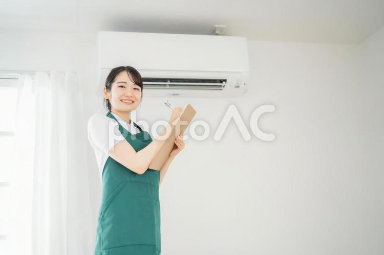 エアコンをチェックする女性（笑顔） エアコン,空調,クーラーの写真素材