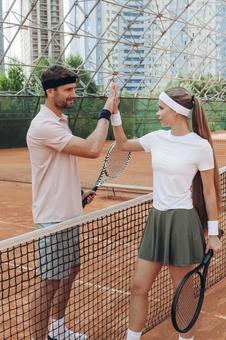 クレイコートで向かい合う男性と女性テニス選手の写真