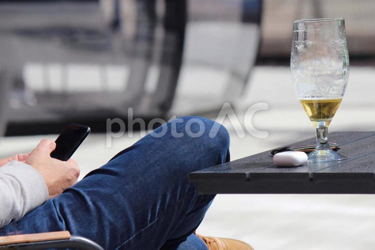ビールを飲みながら携帯をチェックする男性 スマホ,携帯,ビールの写真素材