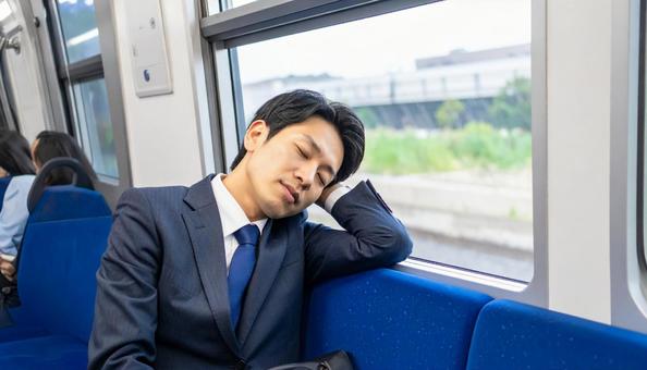 電車で仮眠をする会社員の男性 電車で仮眠をする会社員の男性の写真