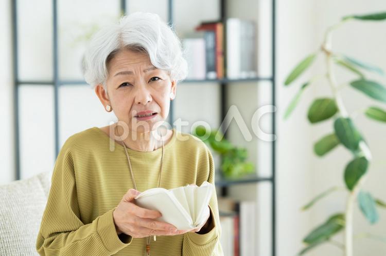 財布を持って悩むシニアの女性 財布,悩む,お金の写真素材