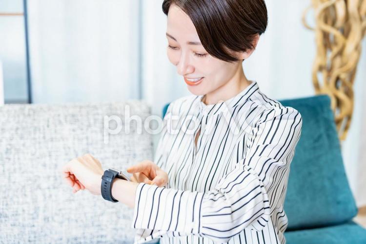 時計を持ちスマートウォッチをつける女性 ヘルスケア,スマートウォッチ,社会人の写真素材