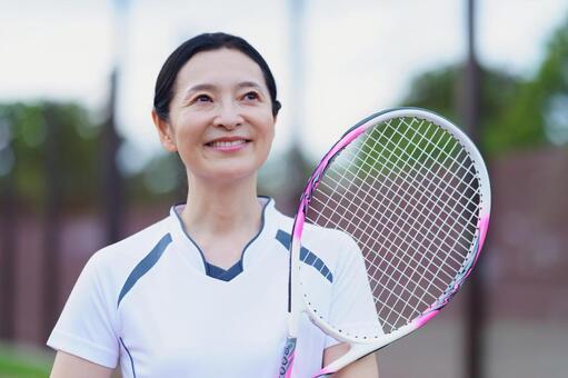 テニスラケットを持ち見上げる女性 女性,テニス,ラケットの写真素材