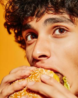 視線が印象的なハンバーガーを食べる男性 視線が印象的なハンバーガーを食べる男性の写真