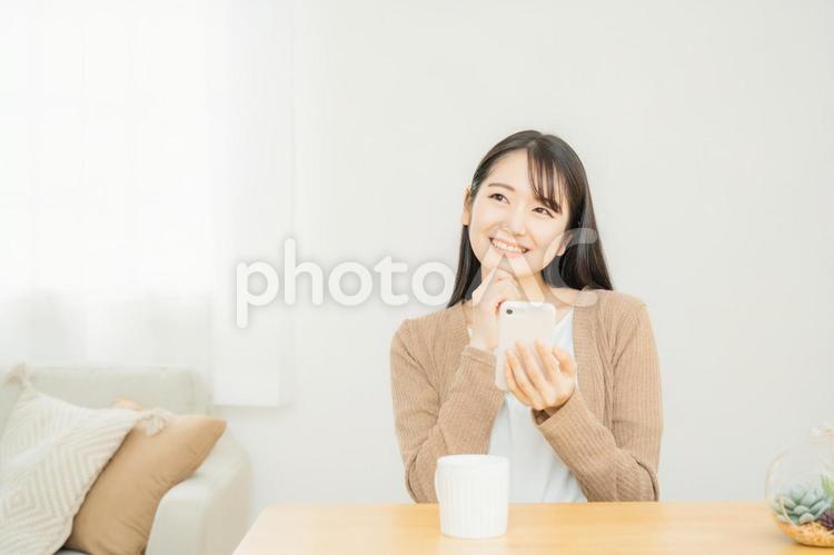 家でスマホを使う女性 スマホ,スマートフォン,笑顔の写真素材