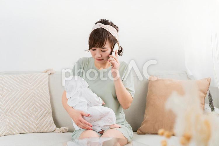赤ちゃんを抱きながら困って電話する女性 赤ちゃん,産後うつ,泣くの写真素材