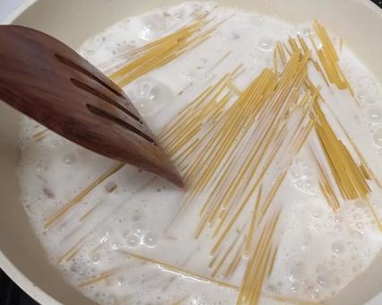 キッチンでクリームソースパスタを作る様子 キッチンでクリームソースパスタを作る様子の写真