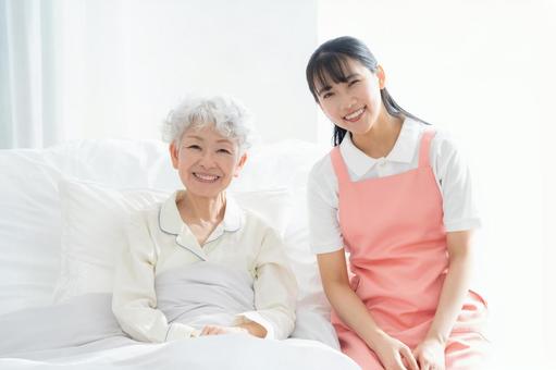 寝ているシニア女性を介護をする介護士 介護,介護士,シニアの写真素材