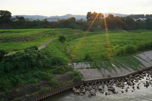 夕陽の光条と河川敷 夕陽の光条と河川敷 夕陽,夕方,夕景の写真素材