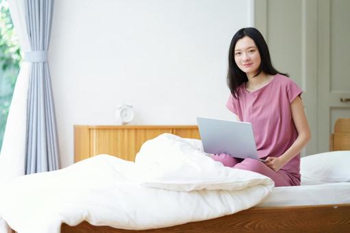 膝の上にパソコンをのせるベッドの女性 女性,ノートパソコン,ベッドの写真素材