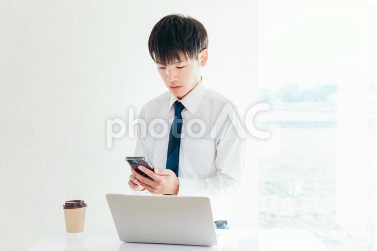 ノートパソコンとスマホを使うビジネスマン 男性,ビジネス,ビジネスマンの写真素材