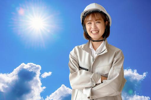 太陽と作業員女性 女性,作業服,ヘルメットの写真素材