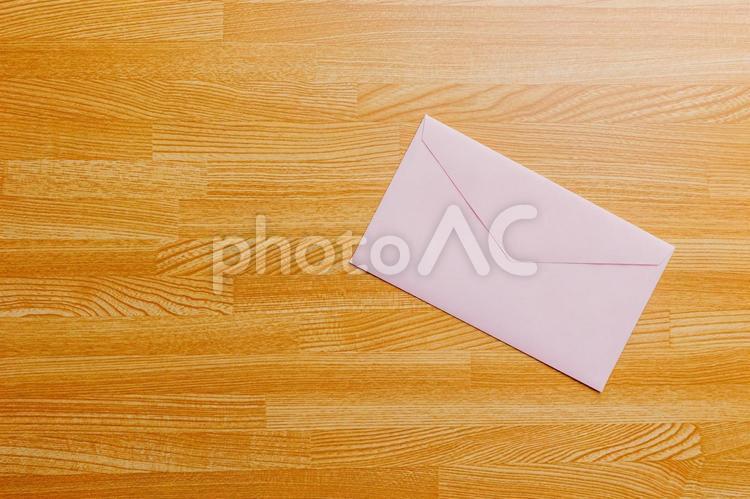 机に置かれたピンク色の封筒 封筒,手紙,レターの写真素材