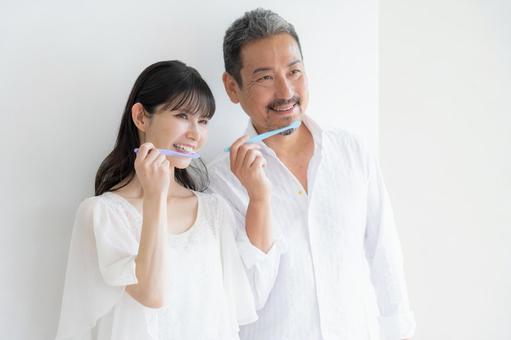白バックで歯磨きをするミドルの夫婦 白バックで歯磨きをするミドルの夫婦の写真