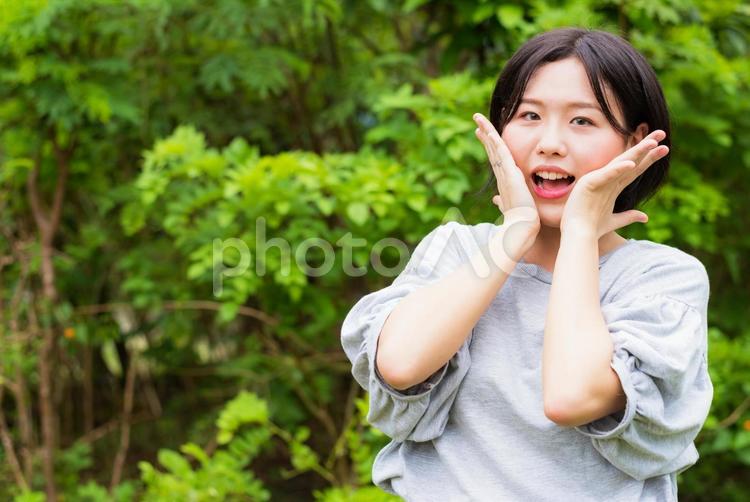 両手を顔に添えて喜ぶ若い女性 女性,笑顔,若いの写真素材