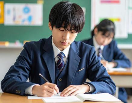 集中して教室で授業を受ける制服の男子学生 集中して教室で授業を受ける制服の男子学生の写真