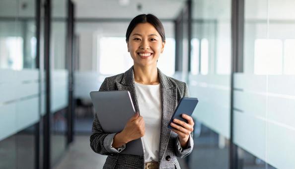会社でPCと携帯を持つビジネスウーマン 会社でPCと携帯を持つビジネスウーマンの写真