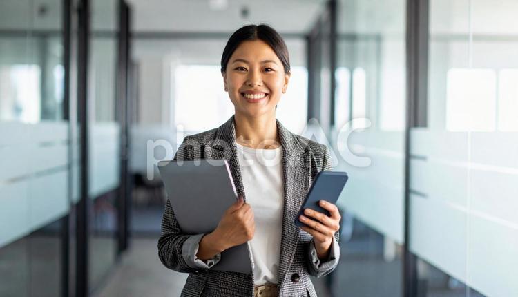 会社でPCと携帯を持つビジネスウーマン 女性,ビジネス,笑顔の写真素材