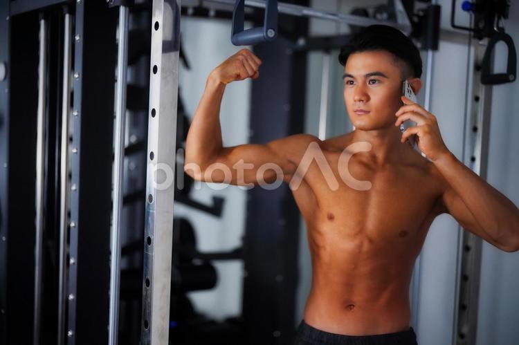 通話しながら力こぶをする男性 男性,ボディビルダー,スマホの写真素材
