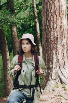 森の中でリュックを背負って歩く女性の写真