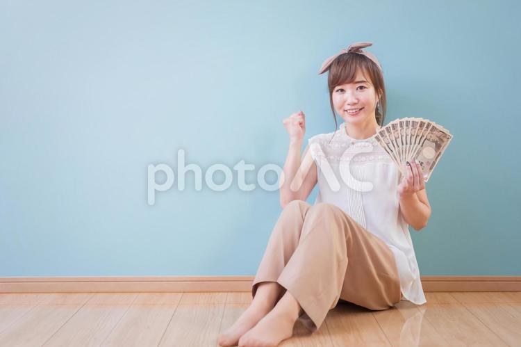お金を持ってガッツポーズをする笑顔の女性 お金,女性,笑顔の写真素材
