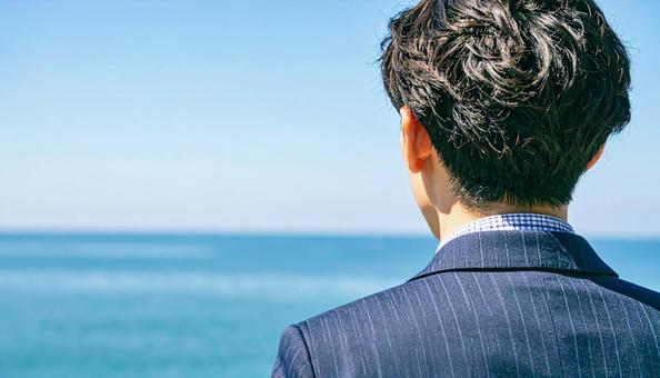 未来を見つめ希望を抱くビジネスマン後ろ姿の写真