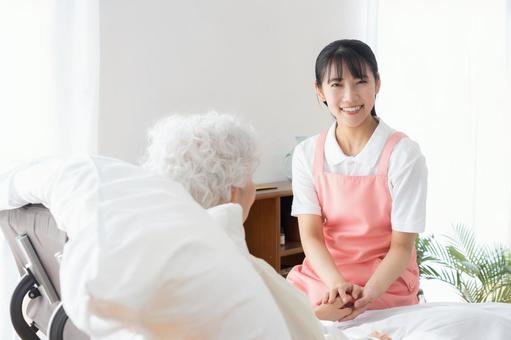 寝ているシニア女性を介護をする介護士 介護,介護士,シニアの写真素材