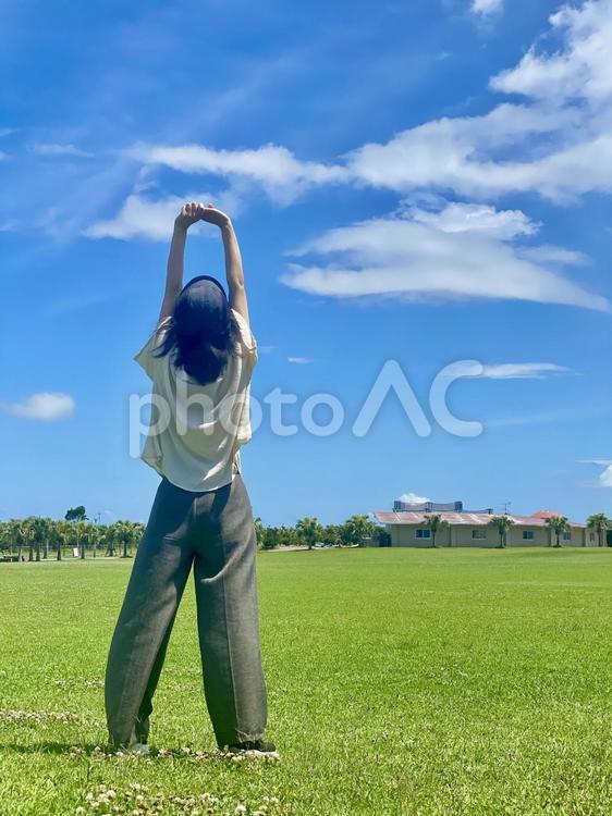青空の下、背伸びをする女性 背伸び,女性,青空の下の写真素材