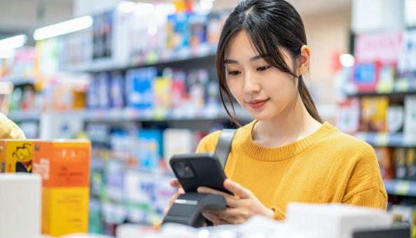 スーパーでスマホ決済を使う若い日本人女性 スーパーでスマホ決済を使う若い日本人女性の写真