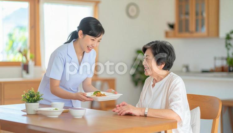 笑顔で食事を運ぶ女性介護士と高齢女性 女性介護士,訪問介護,在宅介護の写真素材