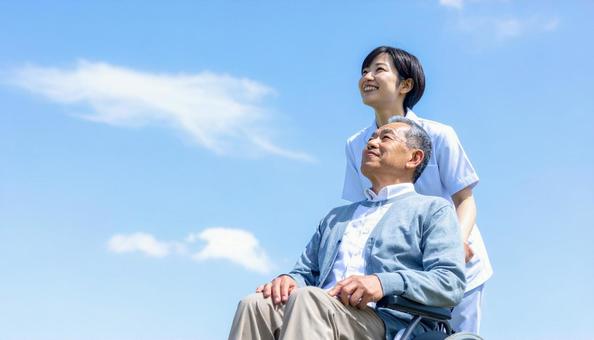 青空を見つめる車いすシニアと介護の女性 青空を見つめる車いすシニアと介護の女性の写真