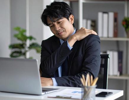 辛い肩凝りで苦しむ男性の写真