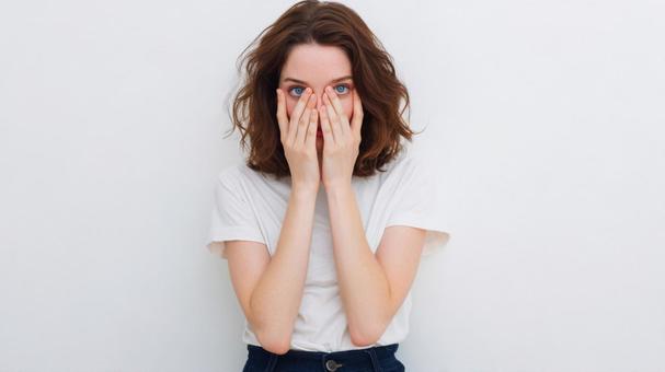 困惑した表情で顔に手を当てる女性 困惑した表情で顔に手を当てる女性の写真