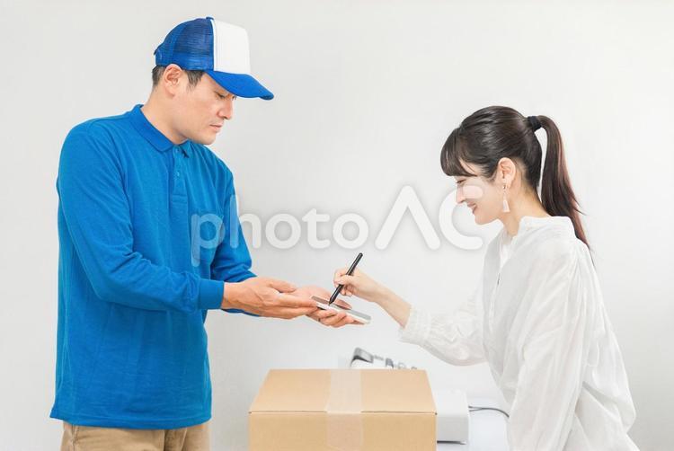 宅配便・荷物を受け取ってサインをする女性 宅急便,宅配便,電子サインの写真素材