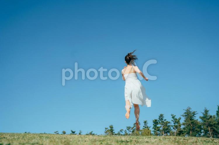 空と白いワンピースで走る女性 女性,走る,空の写真素材