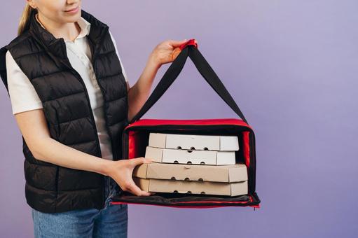 保温ピザバッグを持つ女性配達員の写真