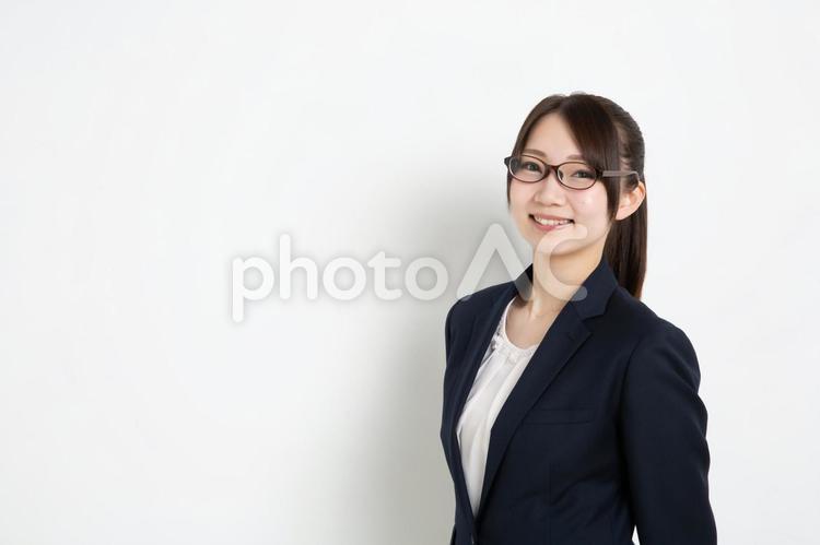 両手を後ろに組み笑っているメガネのビジネスウーマン（コピースペース） 女,女性,日本人の写真素材