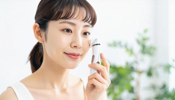 電気シェーバーで顔剃りする若い日本人女性 電気シェーバーで顔剃りする若い日本人女性の写真