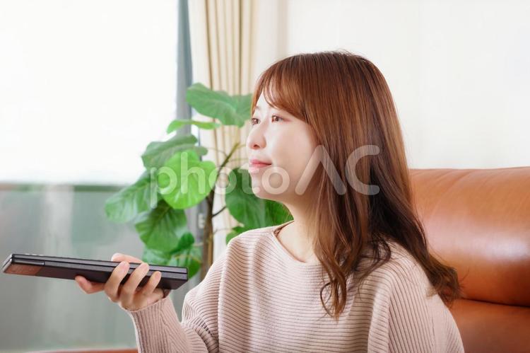 ソファーに座ってテレビを見る女性 テレビ,ブルーレイ,チャンネルの写真素材