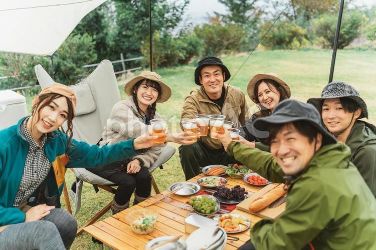 秋冬のキャンプ場で仲間と乾杯する男女 キャンプ,ビール,バーベキューの写真素材